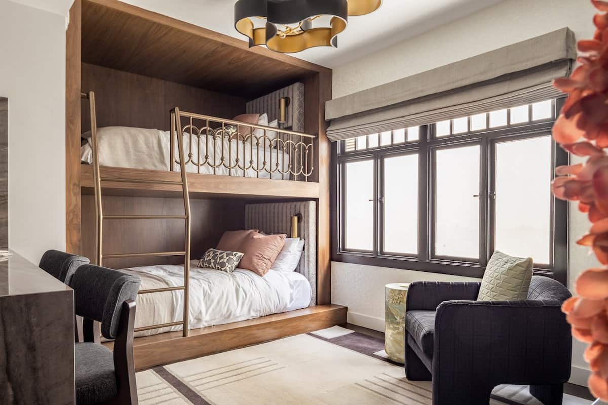 Modern bunk bed setup in a stylish hotel suite with cozy bedding, large windows, and contemporary seating area
