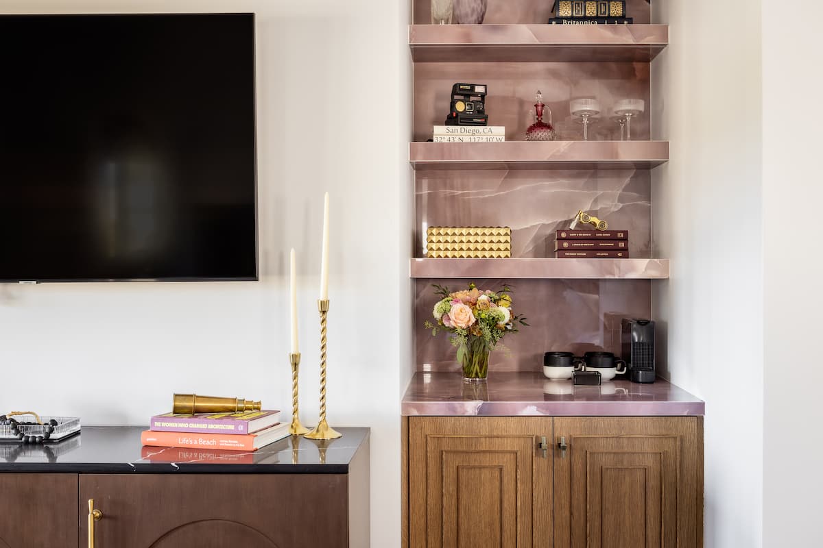 Built-in shelving with decorative objects, books, and flowers beside a wall-mounted TV in a luxury hotel suite