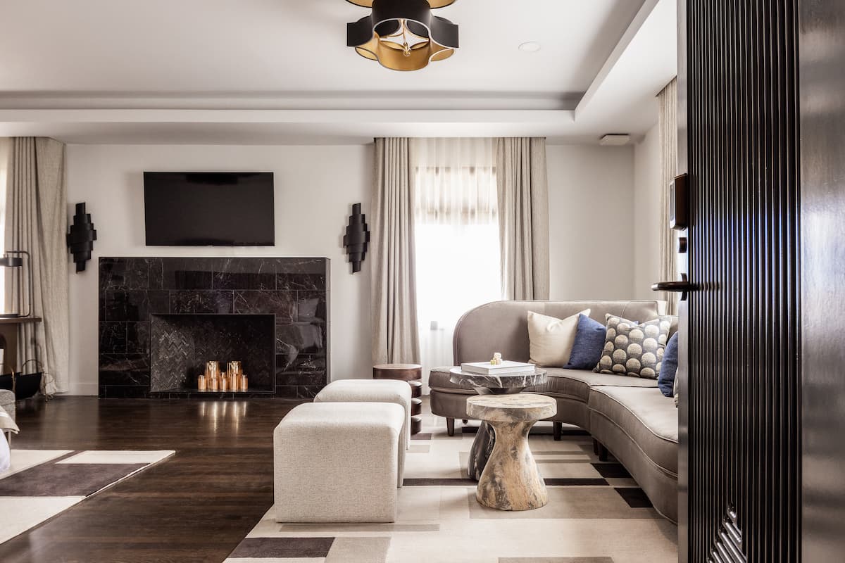 Refined hotel living room with a modern fireplace, neutral seating, patterned rug, and soft natural light creating an inviting atmosphere