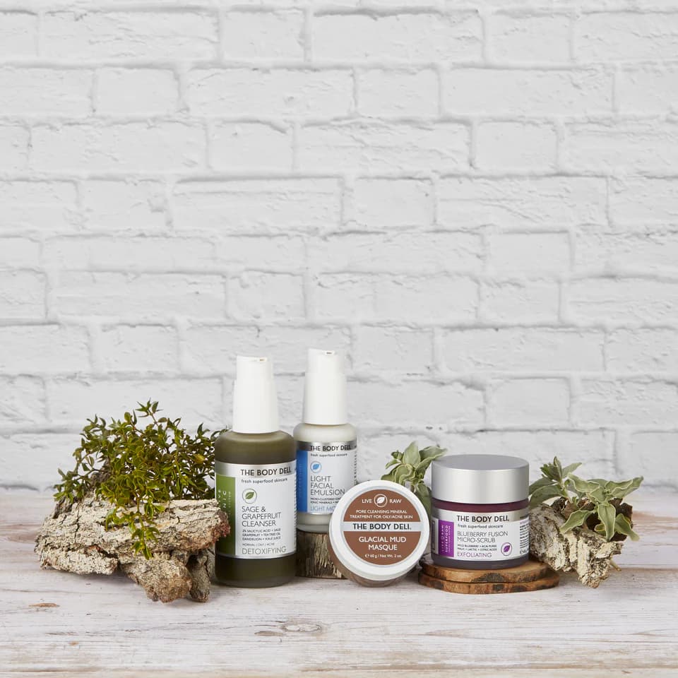Natural skincare products displayed with botanical elements on a wooden surface against a white brick background
