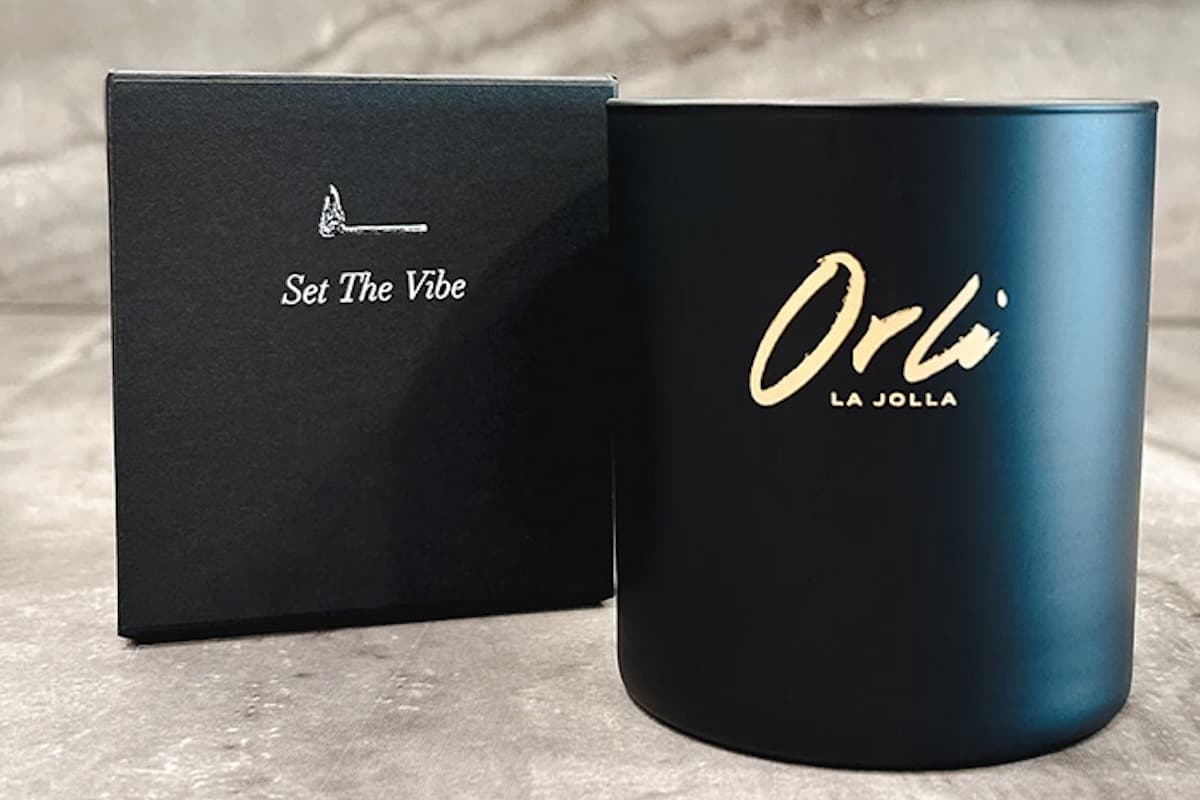 Black Orli La Jolla scented candle with gold logo displayed beside its box featuring the phrase “Set The Vibe”