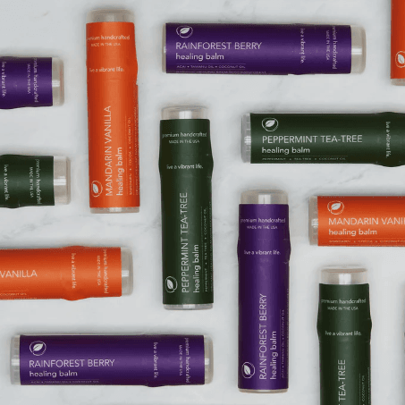 Assorted natural healing balm tubes in vibrant colors arranged in a flat lay on a light background